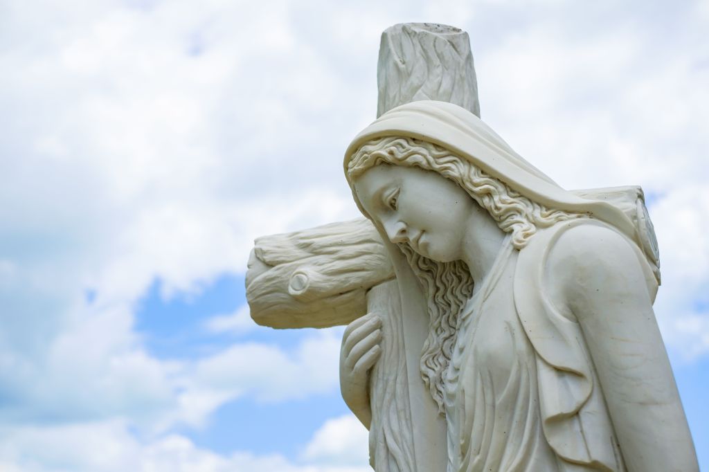 Religious sculpture of a woman carrying a cross.
